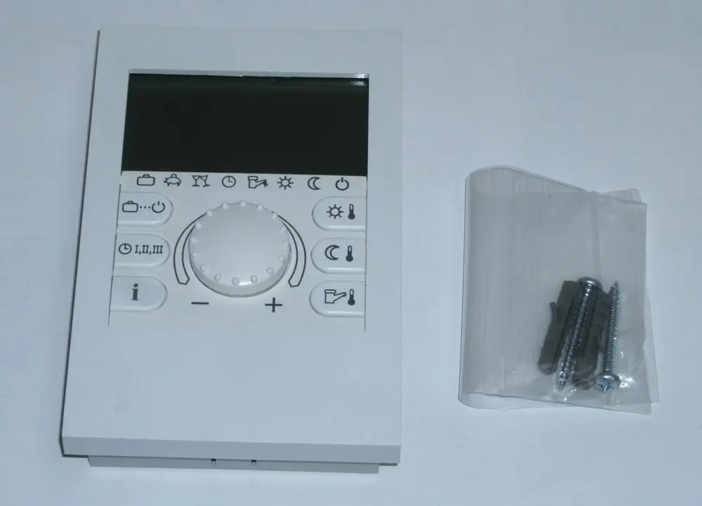 Weißes Bedienelement mit Display und verschiedenen Symbolen, darunter Einstellknopf und Funktionstasten, neben einer Tüte mit Montagematerial von Daikin.